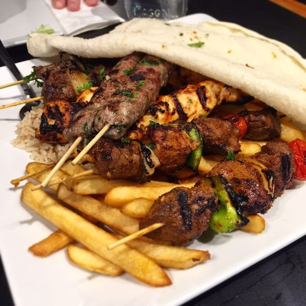 Platter of Yalla Grill's Lebanese grilled meat skewers, fries, rice, and pita bread.