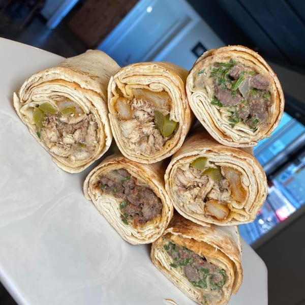 Six Lebanese shawarma wraps, some with chicken and pickles, others with beef and herbs, on a white plate.