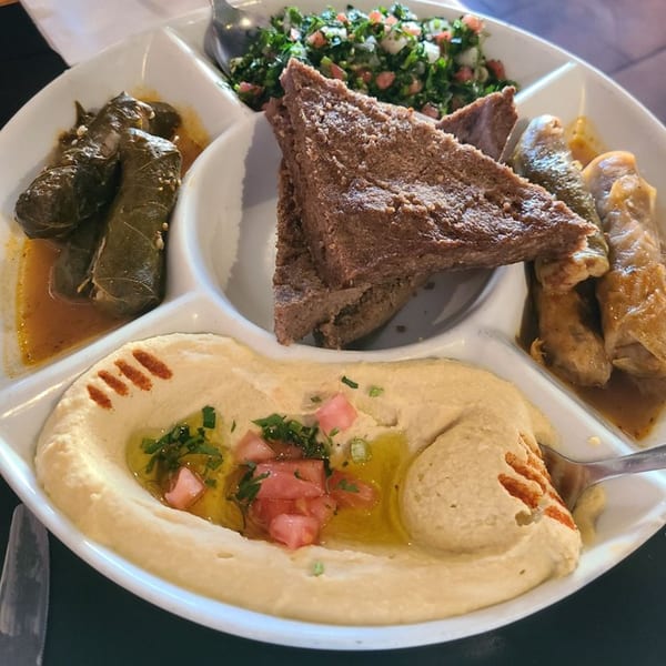 A Lebanese mezze platter with hummus, tabbouleh, kibbeh, stuffed grape leaves, and cabbage rolls.